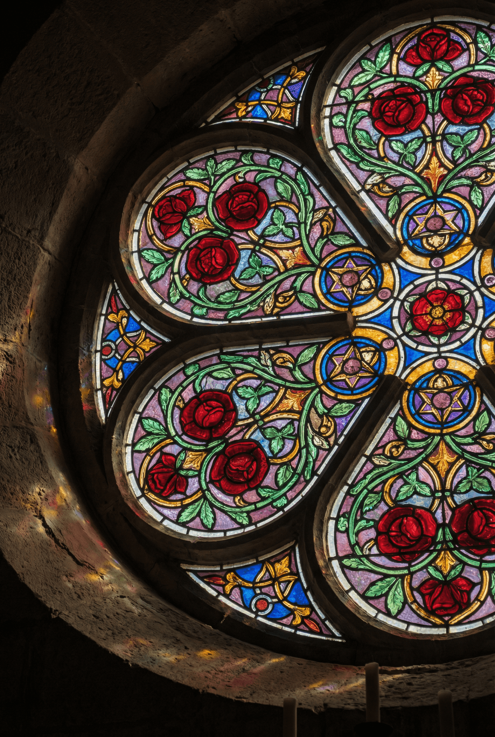 A circular stained glass window design featuring intricate red roses and green vines, vibrant translucent colors, bold b