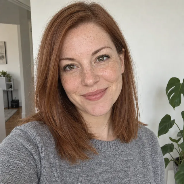 Synthetic source photo: a fictional woman with shoulder-length auburn hair and freckles in a grey sweater
