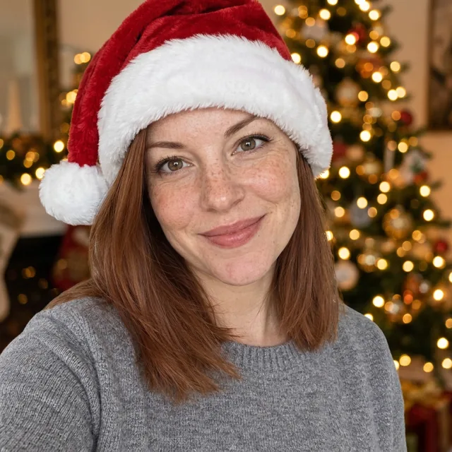 The same woman in a red Santa hat with a lit Christmas tree behind her