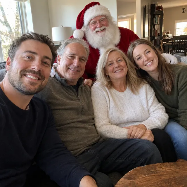 Santa Claus behind the sofa resting his hands on two family members’ shoulders