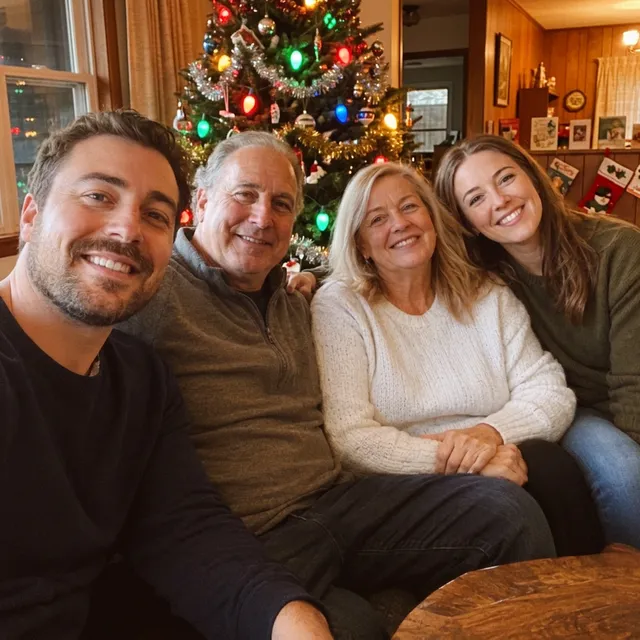 The same four people in a warm, grainy 1970s-style photo with tinsel and a tree with large coloured bulbs
