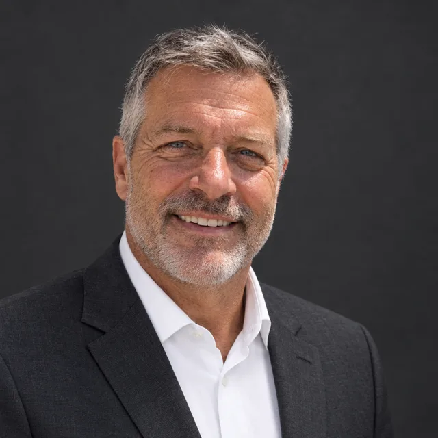 The same man in a charcoal jacket on dark grey, with more skin texture