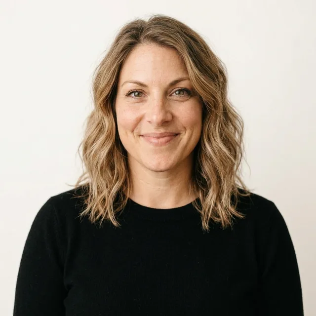 The woman in a black crew-neck sweater on a warm white backdrop