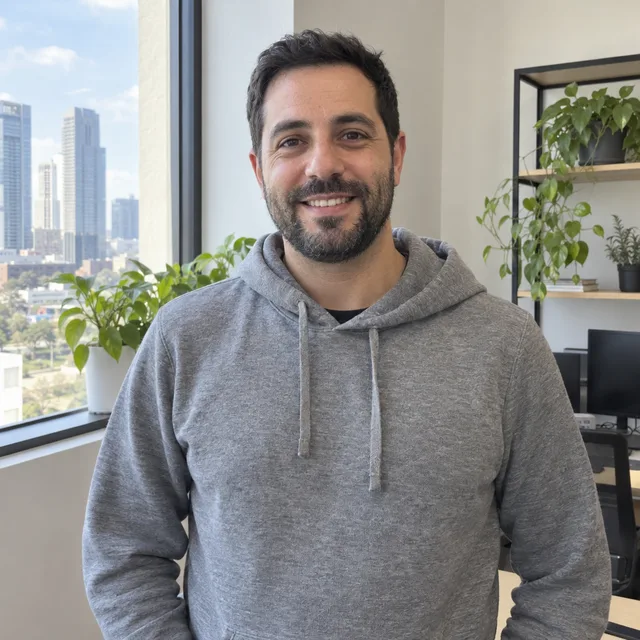 Synthetic source photo: a fictional bearded man in a grey hoodie in a bright office
