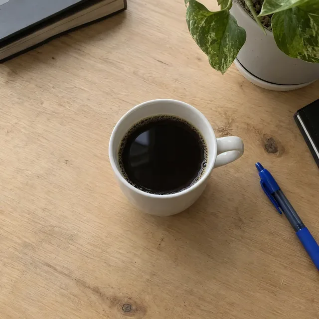 Dieselbe Tasse auf einem aufgeräumten Holzschreibtisch, fast gleich wie das andere Ergebnis