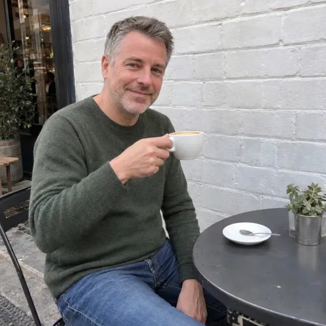 Le même homme à la table devant un mur de briques blanches propre