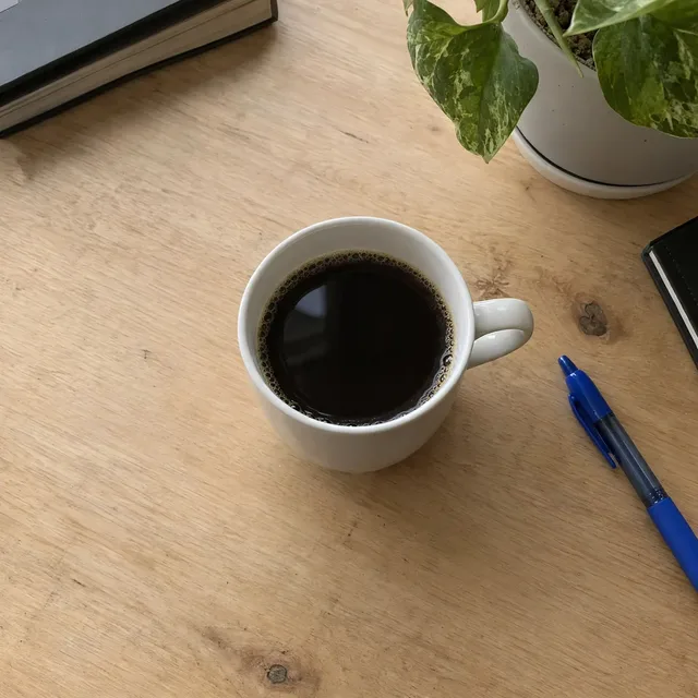 La stessa tazza su una scrivania di legno pulita, quasi identica all’altro risultato