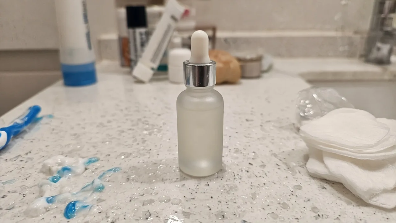 Frosted serum bottle on a cluttered bathroom counter